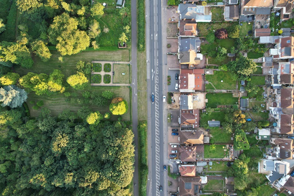 Aerial view of a small town in Roehampton, showing a mix of mid-rise and low-rise brick buildings, residential houses, and commercial properties along a central road. The image captures a busy loading